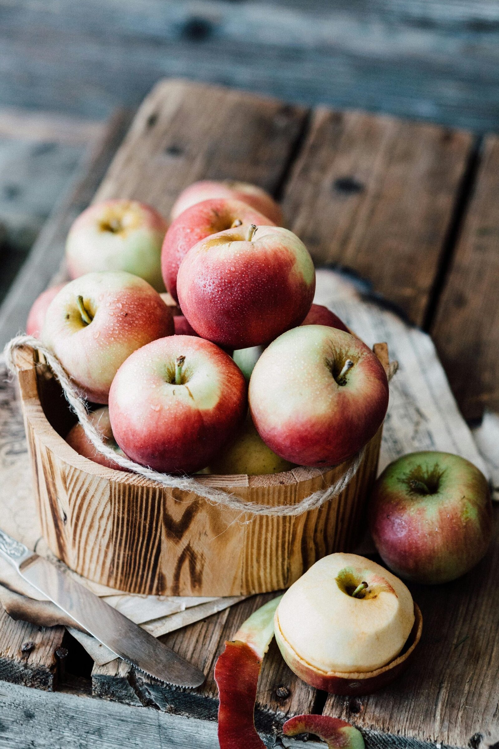 A close-up of ripe apples in a wooden basket on rustic planks. Ideal for fall harvest themes.